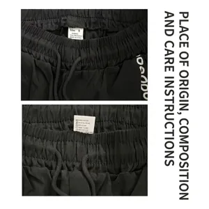 Close-up of waistband and care label on men's black harem pants showing material details