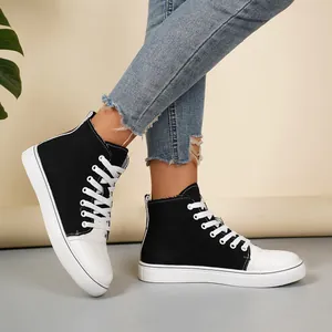 Detailopname van stijlvolle zwart-witte high-top canvas sneakers met jeans aan.