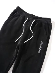Detail of black fleece sweatpants featuring white drawstrings and side pocket
