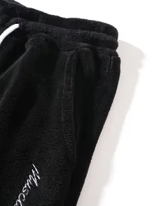 Close-up of black fleece joggers with white drawstring and embroidered logo detail