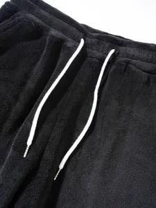 Close-up detail of men's black sweatpants featuring soft fleece texture and white drawstring.