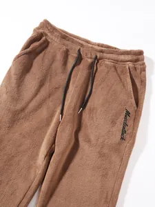 Close-up detail of brown fleece sweatpants with drawstring waist and Muscleattack logo