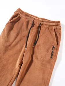 Detail of brown plush men's sweatpants with drawstring waist and Muscleattack embroidery