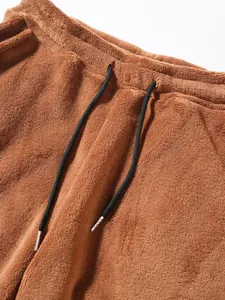 Detailed close-up of men's brown plush joggers featuring black drawstring with metal tips