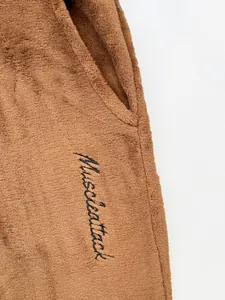 Detail view of men's brown fleece joggers with Muscleattack embroidery and pocket