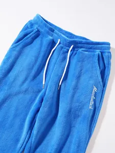 Close-up detail of blue fleece joggers with white drawstring and muscleattack embroidery
