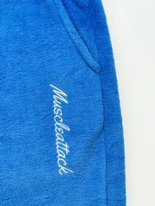 Close-up of Muscleattack embroidery on blue fleece men's jogging pants with pocket