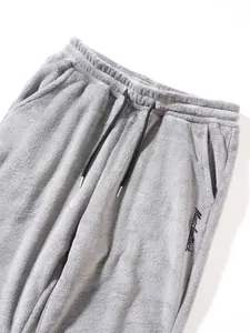 Close-up of men's gray fuzzy fleece pants detailing black drawstring and side embroidery