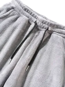 Close-up of grey plush fleece jogger pants with elastic waistband and black drawstrings.