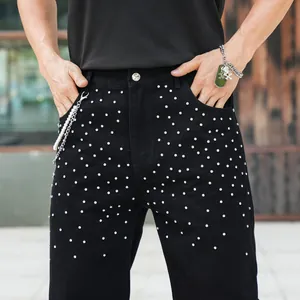 Close-up of sparkling rhinestone details on men's black loose fit denim jeans