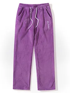 Close-up view of purple fuzzy men's sweatpants featuring white drawstring and embroidery.