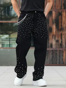 Detail view of men's loose black jeans with sparkling rhinestone studded patterns.