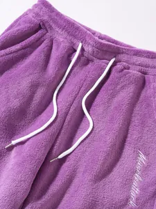 Close-up view of purple fleece sweatpants with drawstring and embroidery detail.