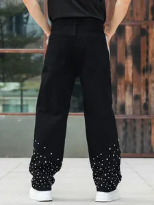Back view of black loose-fit jeans for men featuring sparkling rhinestone studs at the cuffs