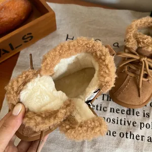 Close-up showing the thick warm plush lining inside brown winter snow boots for toddlers.