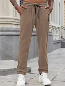 Detail view of brown fleece joggers with 'Muscleattack' embroidery and drawstring