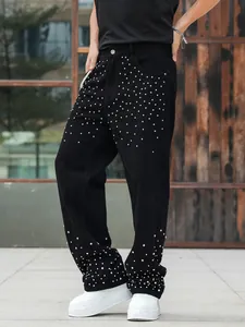 Detail of men's loose straight-leg black jeans with silver rhinestone stud accents.