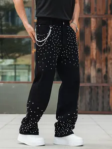 Detail of men's black straight-leg jeans with silver rhinestone studs and decorative pearl chain
