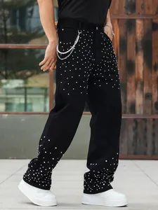 Detail view of men's black straight jeans with sparkling rhinestone embellishments.