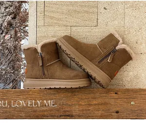 Detail view of warm brown suede snow boots with faux fur lining and side zippers.