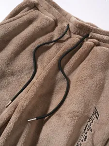 Detailed macro shot of brown coral fleece sweatpants with black drawstring and embroidery detail.