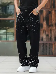 Detailed view of men's loose straight black jeans featuring sparkling rhinestone studs