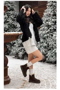 Model wearing brown fur-lined snow boots in a snowy winter outdoor scene