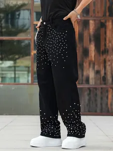 Detail shot of men's loose black jeans featuring sparkling silver rhinestone studs