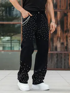 Close-up detail of men's loose straight jeans with sparkling rhinestone embellishments.