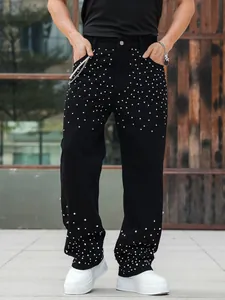 Detail of men's loose straight-leg black denim pants with rhinestone embellishments.