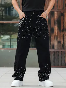 Detail view of men's black straight-leg jeans with sparkling rhinestone studs.