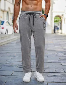 Macro view of men's grey fleece joggers with black drawstring and logo embroidery