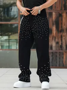 Detailed view of men's loose black denim jeans featuring sparkling rhinestone embellishments.