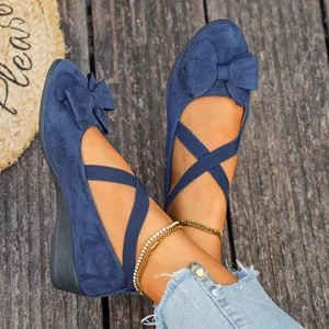 Vista dettagliata di scarpe con zeppa in camoscio blu con cinturini incrociati e fiocchi