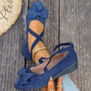 Primo piano di eleganti ballerine blu in pelle scamosciata con fiocco e cinturini elastici