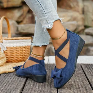 Dettaglio di scarpe con zeppa in camoscio blu con fiocco e cinturini elastici incrociati