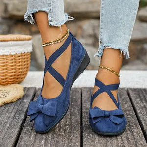 Dettaglio scarpe con zeppa in camoscio blu con cinturini incrociati e fiocco decorativo