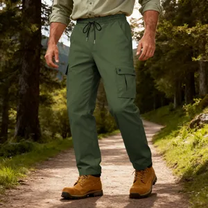 Dettaglio dei pantaloni cargo tattici da uomo verde oliva in un ambiente forestale naturale