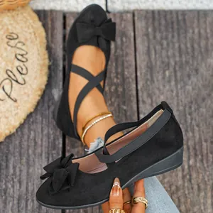 Dettaglio di scarpe con zeppa in camoscio nero con fiocco elegante e cinturini elastici incrociati