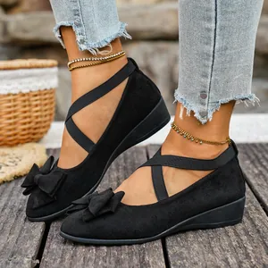 Dettaglio ravvicinato di scarpe con zeppa in finta pelle scamosciata nera con fiocco