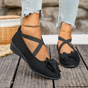 Vista dettagliata delle scarpe zeppa in camoscio nero con fiocco e cinturini elastici