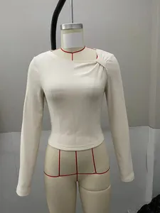 Close-up of cream ribbed knit top with unique asymmetrical neckline and knot detail