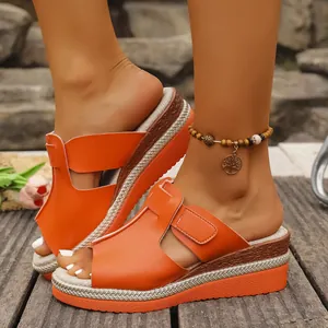 Vue détaillée de sandales compensées orange avec bandes velcro sur terrasse en bois