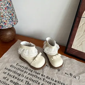 Detail van beige meisjes Martin laarzen met kanten ruches en strikaccenten op linnen doek