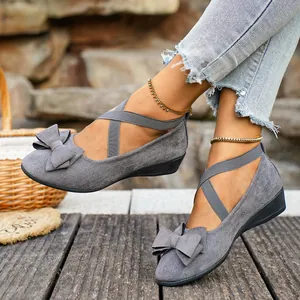 Vista laterale di ballerine con zeppa in camoscio grigio con fiocco e elastici