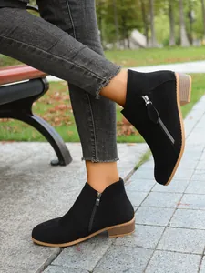 Close-up of women's black suede ankle boots with side zipper and chunky low heel