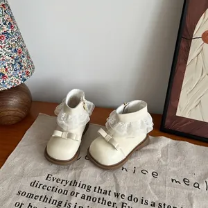 Detailweergave van beige enkellaarsjes voor meisjes met kanten rand en strikjes