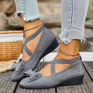 Dettaglio di scarpe con zeppa in pelle scamosciata grigia con fiocco e cinturini incrociati