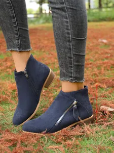 Close-up of navy blue suede ankle boots with double side zippers and low chunky heel