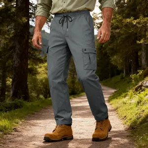 Primo piano dei pantaloni cargo tattici grigi indossati su un sentiero boscoso al sole